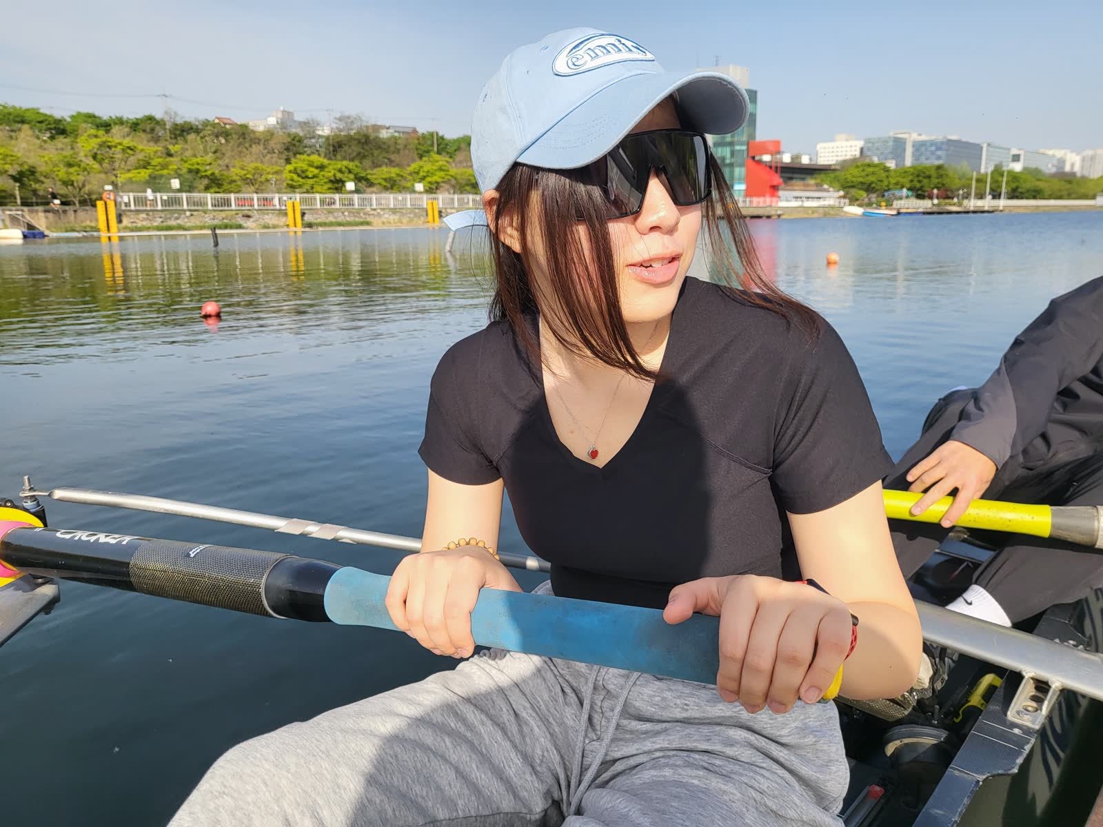 Olivia Yoojin Lee sitting in a scull on the water at Misari, holding the oar handle.